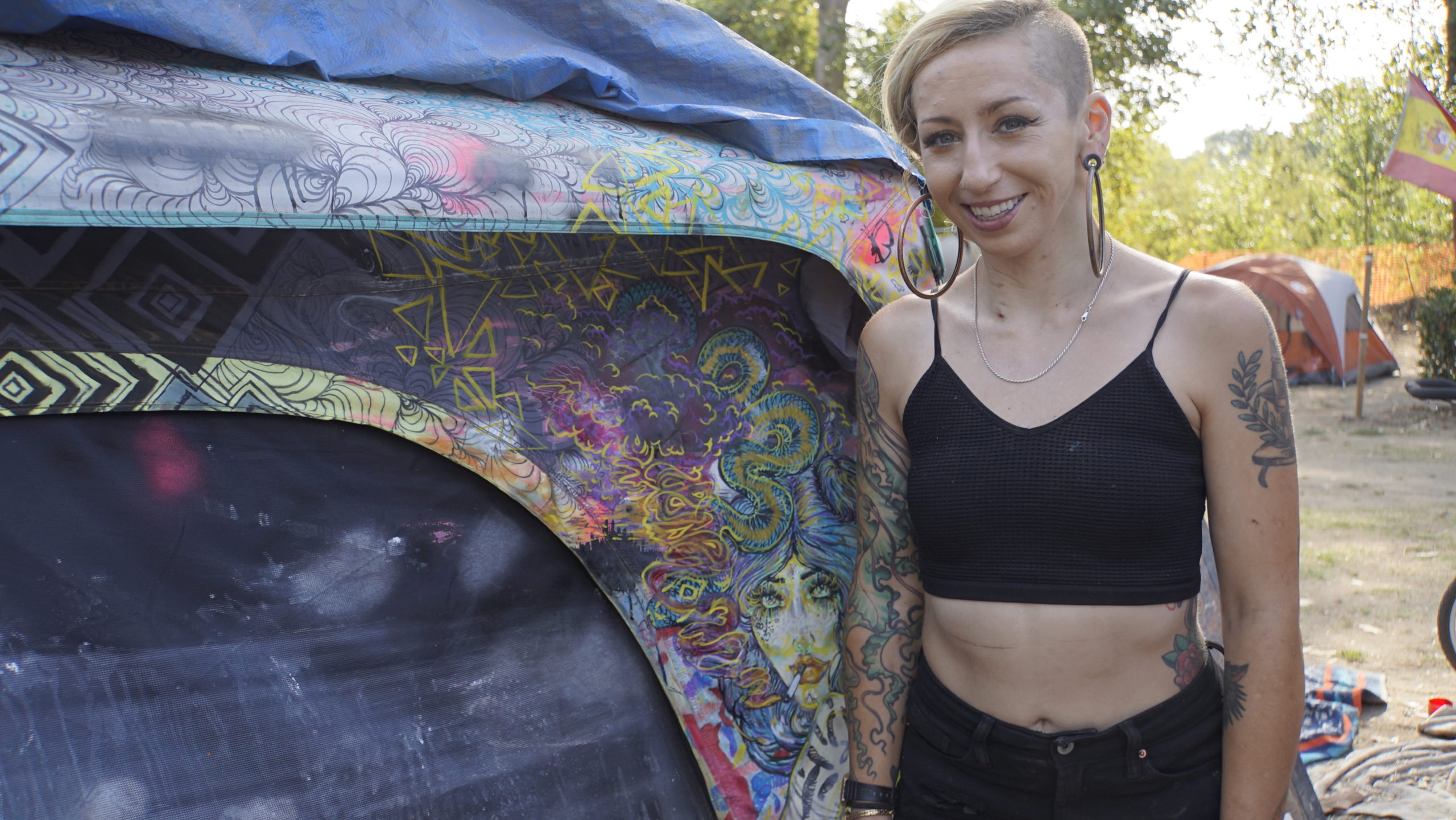 Milan Evje stands next to her tent artwork at the Benchlands homeless camp in Santa Cruz in September 2021