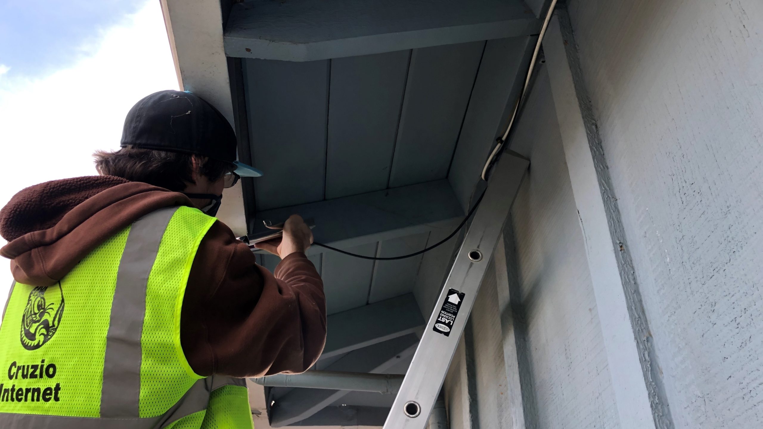 Cruzio Internet technician Jay Varens secures a cable to a home in Watsonville as a part of a program to provide lower-cost internet service. (Alana Matthews — Cruzio Internet)