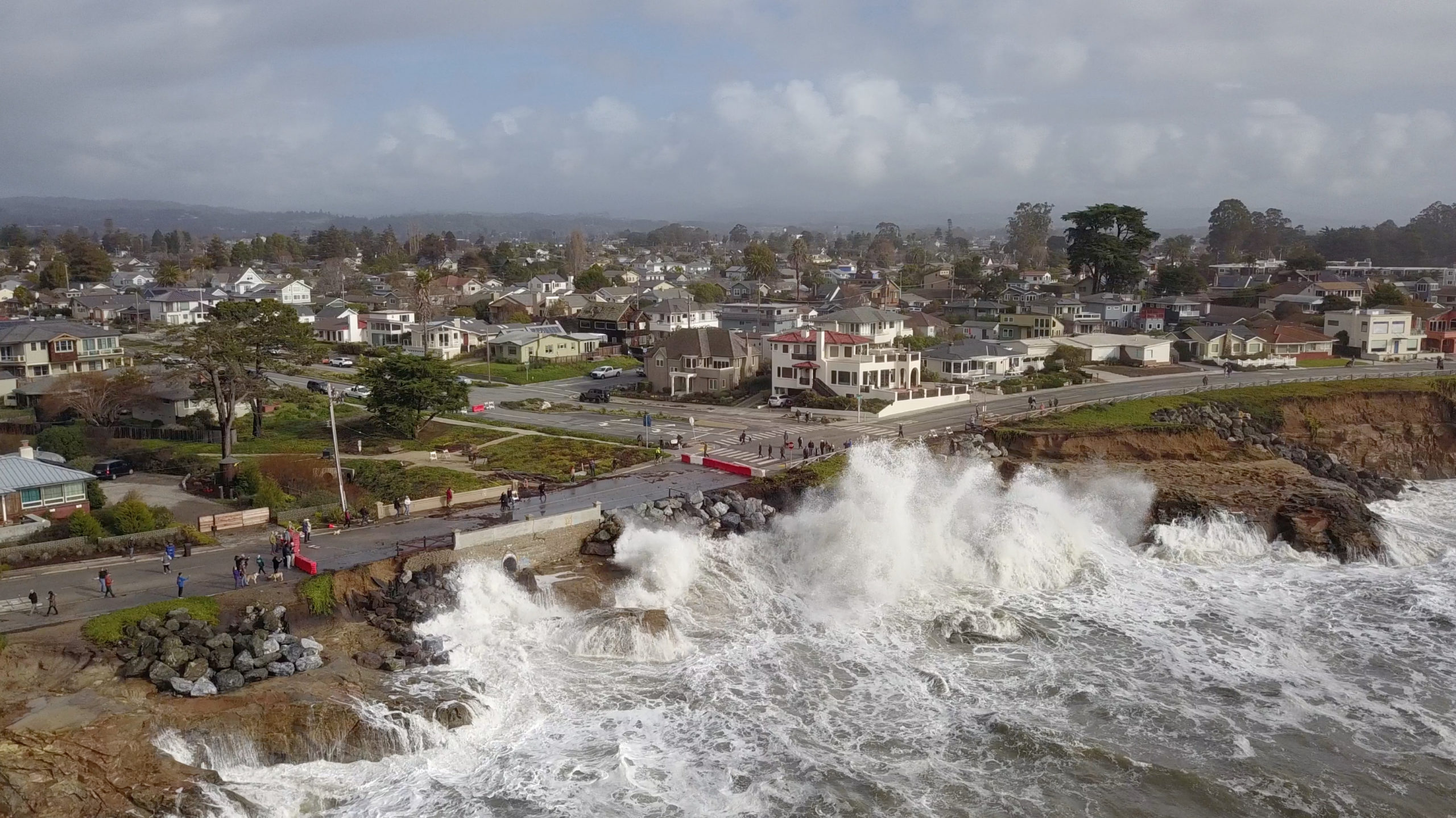 An aerial view shows a large wave crashing on West Cliff Drive in January 2023.