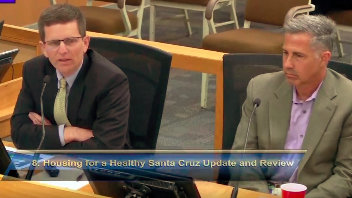A screenshot of the county supervisors meeting's video broadcast shows Robert Ratner and Randy Morris speaking on the agenda item "Housing for a Healthy Santa Cruz Six Month Update and Review."