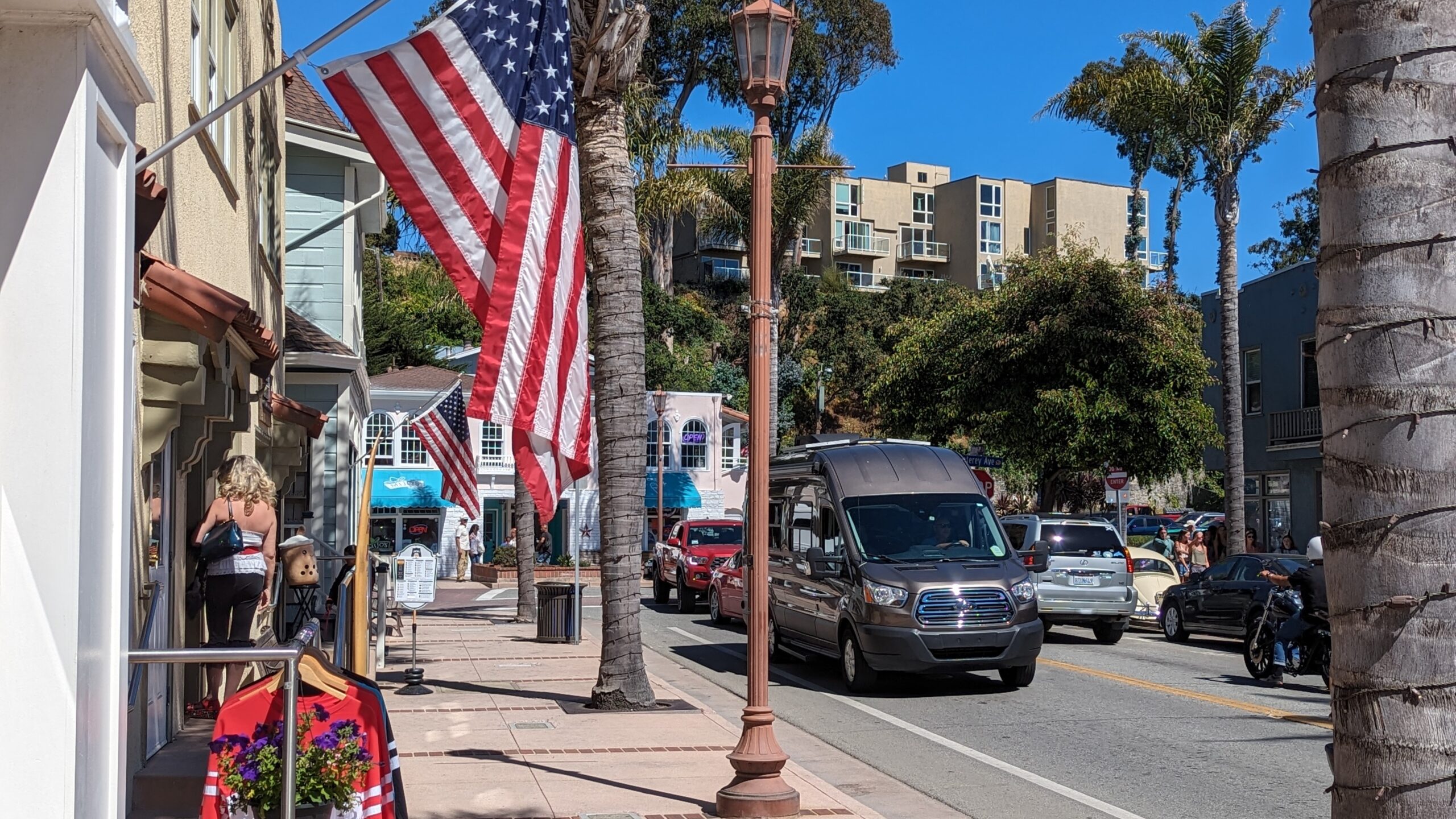 Capitola Village on a sunny day with an American flag hanging from a business and blue skys.