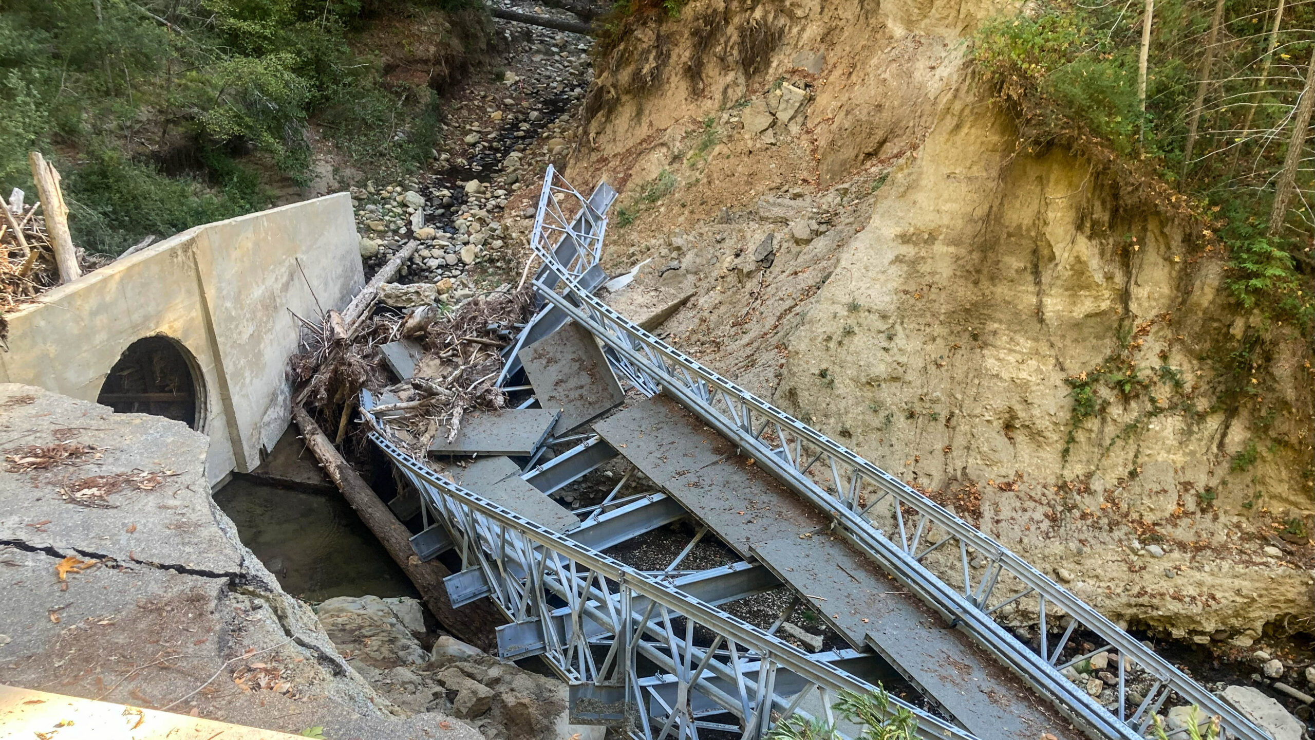 A broken bridge on Redwood Lodge Road that used to cross Lauren Creek is all mangled metal.