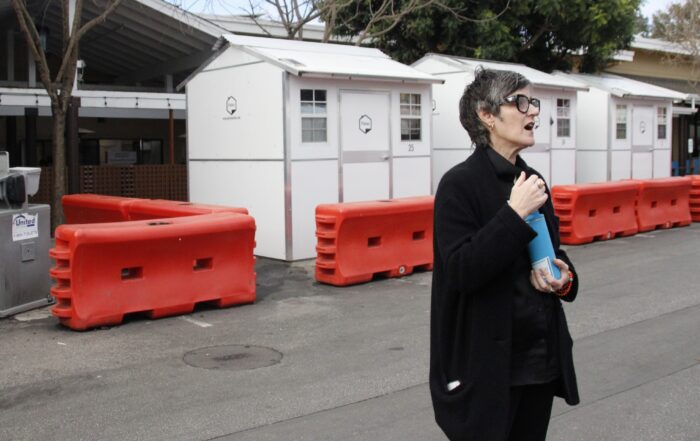 Housing Matters Chief Impact Officer Mer Stafford speaks in front of pallet shelters for unhoused residents at the Housing Matters campus on Coral Street in Santa Cruz in January.