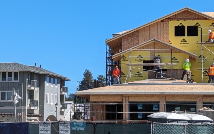Workers install materials on a wall at Aptos Village Phase 2 in March 2024. (Stephen Baxter — Santa Cruz Local)