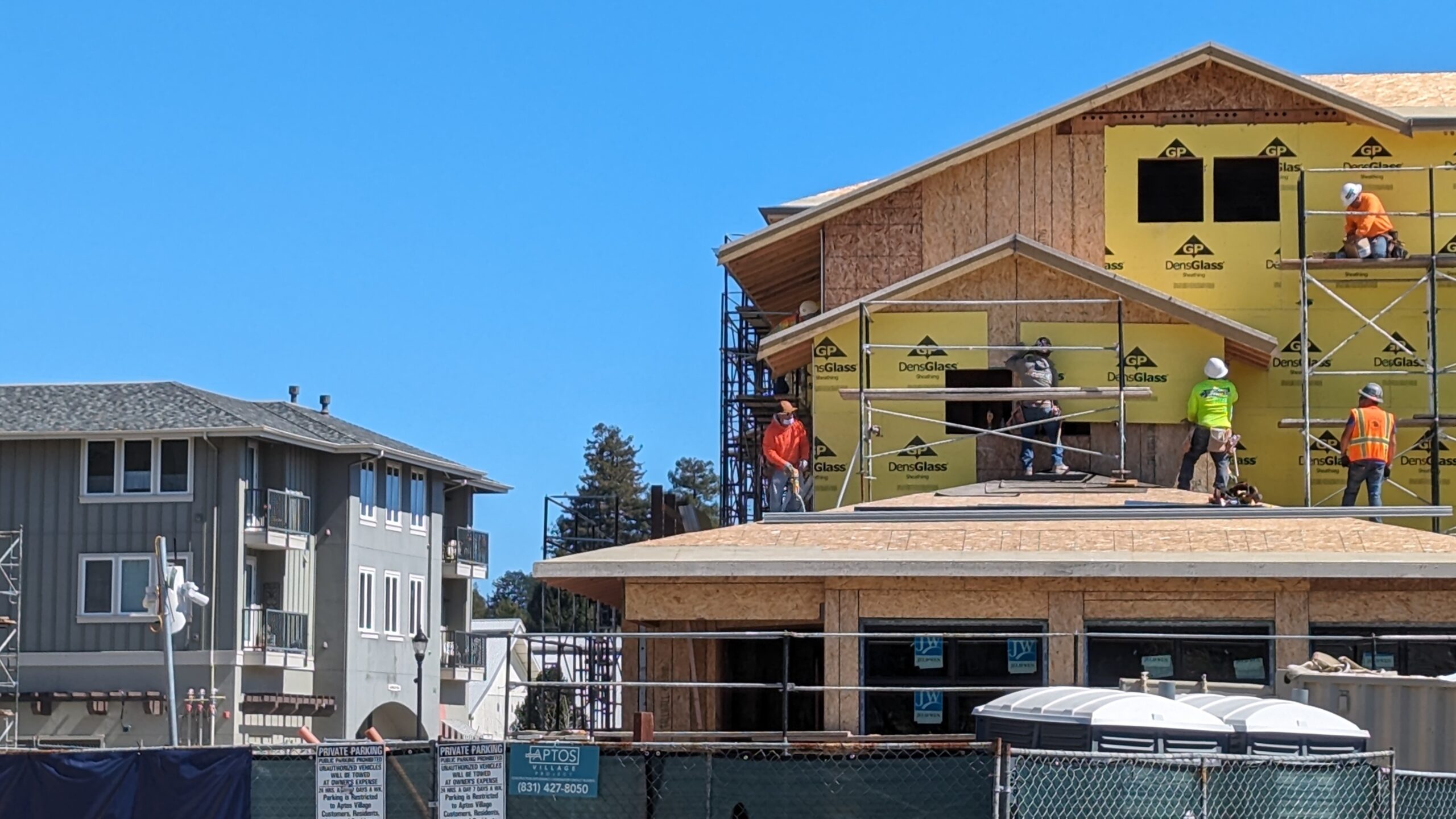 Workers install materials on a wall at Aptos Village Phase 2 in March 2024. (Stephen Baxter — Santa Cruz Local)