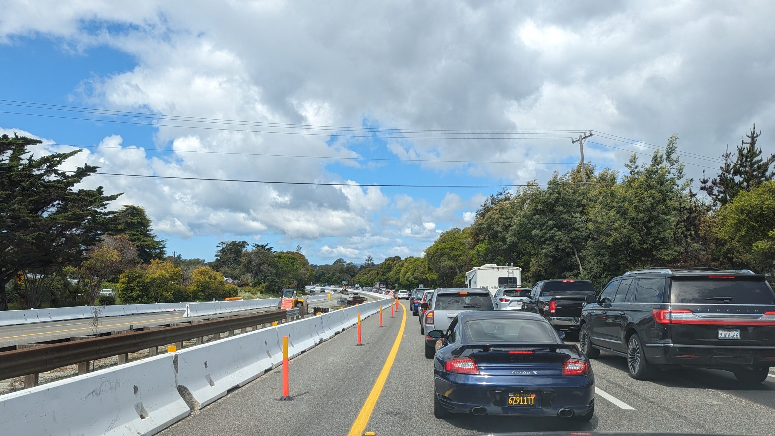 Cars back up on Highway 1 below a beautiful blue sky.