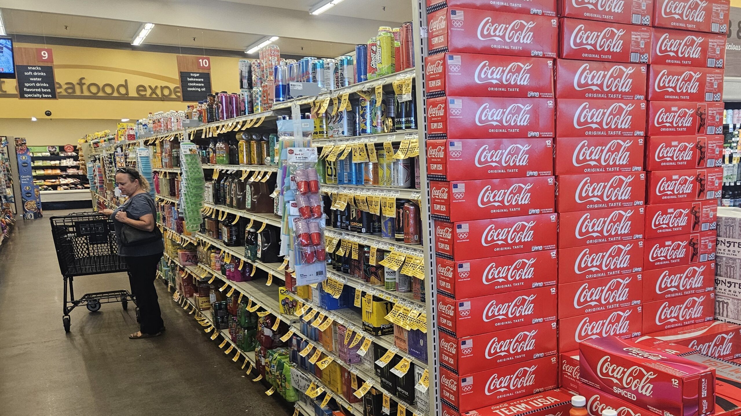 A soda isle at Safeway has stacks of Coca-Cola boxes.