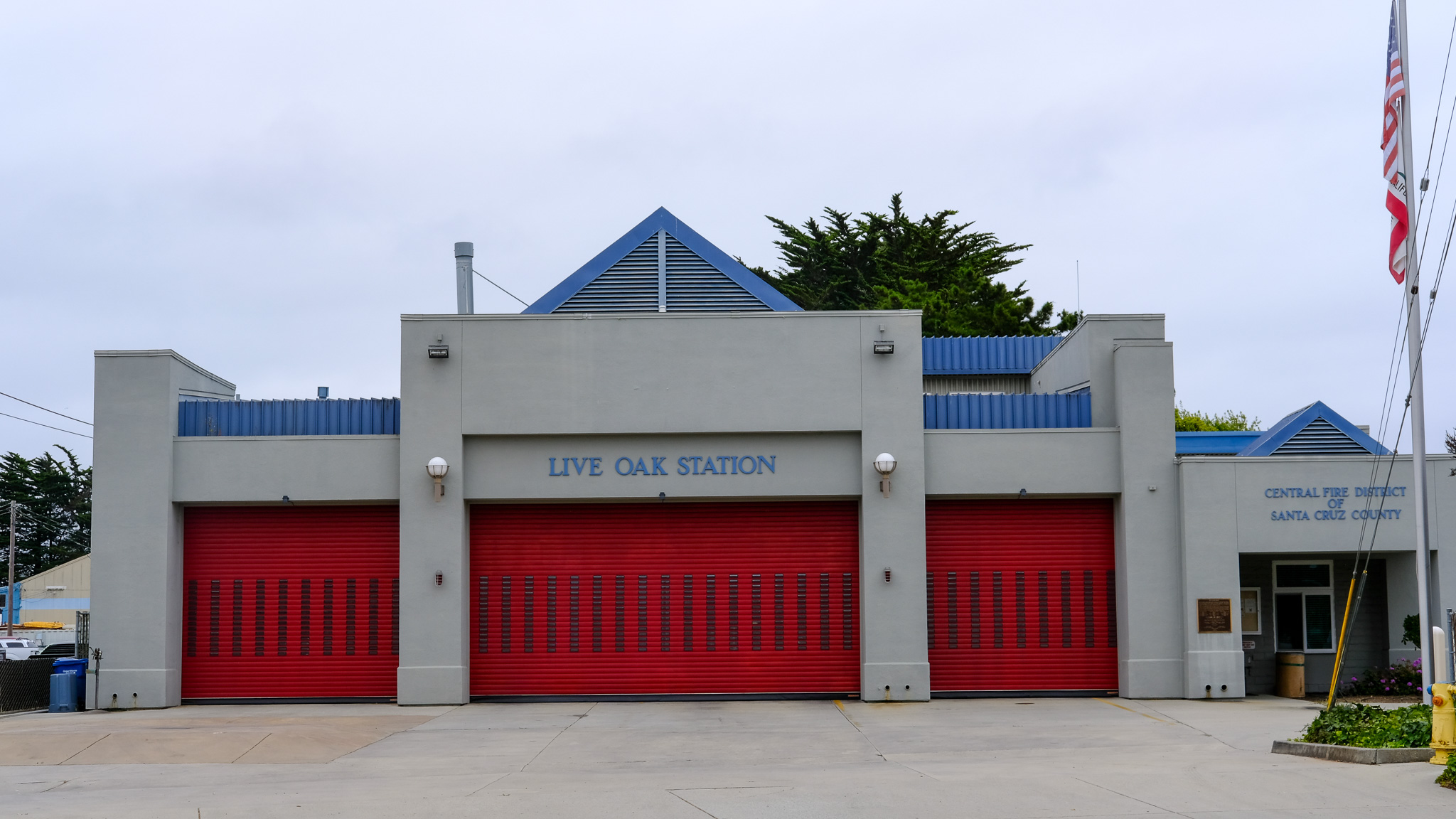 Central Fire District Station 1 is seen on an overcat day, the building is gray with large, red roll-up doors.