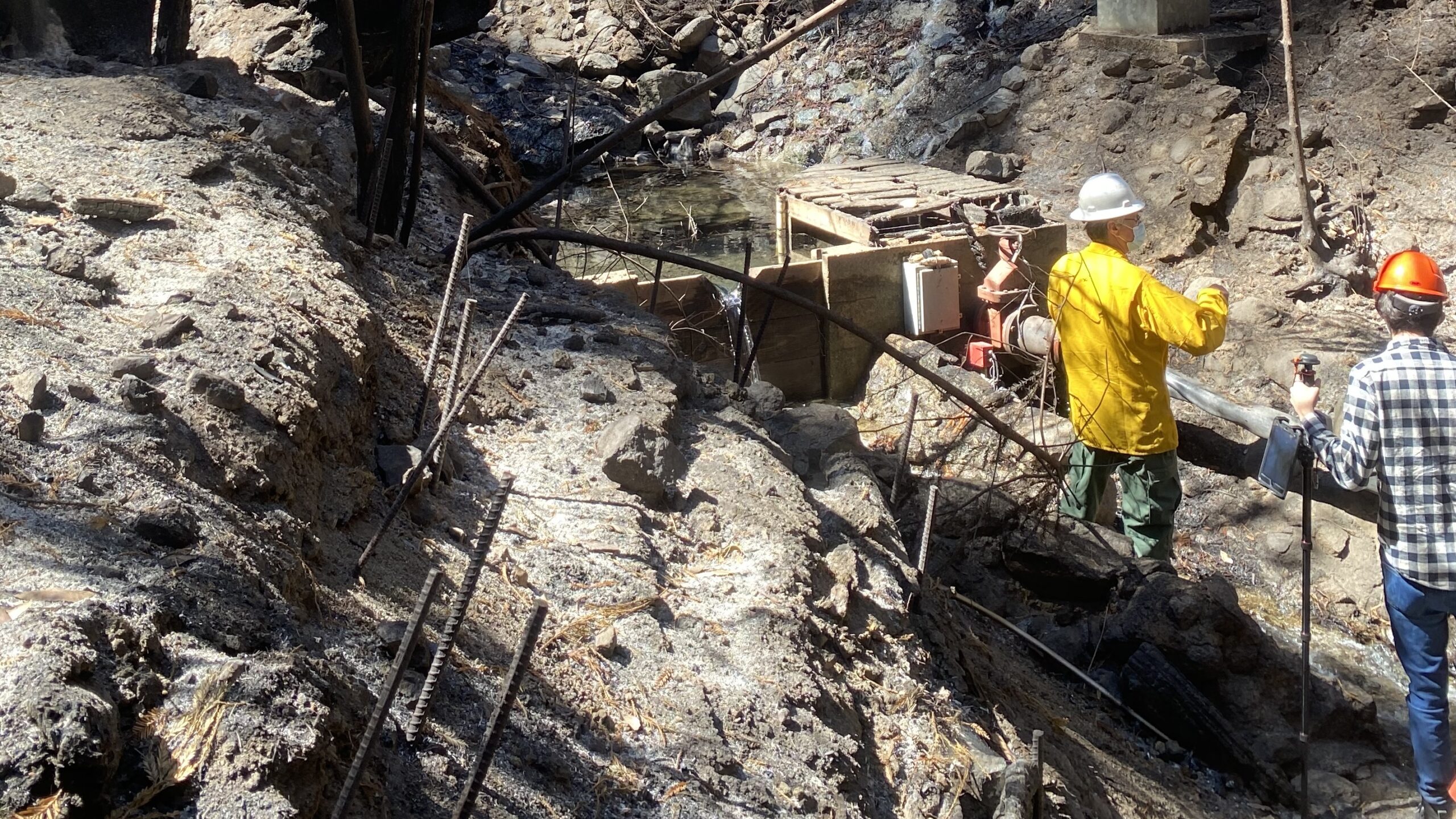 Two people wearing hard hats work on a water pipeline near Ben Lomond.