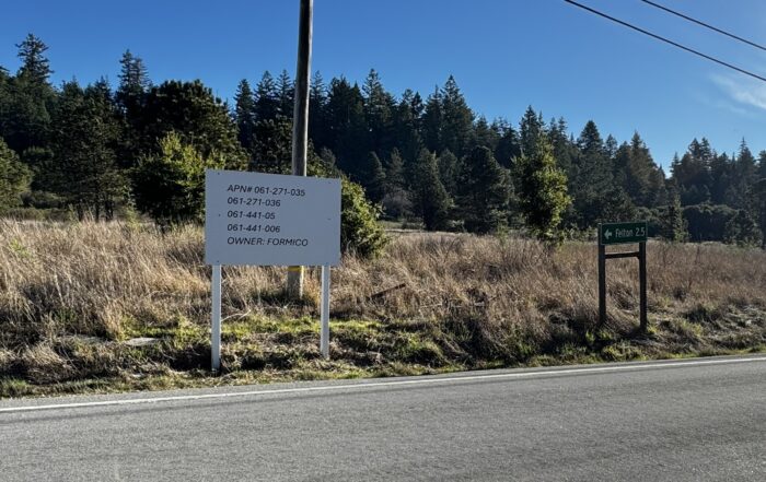 A sign at the edge of Graham Hill Road lists parcel numbers and the property owner's last name.