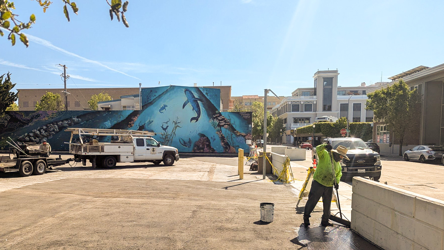 downtown-farmers-market-tyler-maldonado-may-7-2025-6 A worker resurfaces a parking lot next to the Downtown Santa Cruz Library.