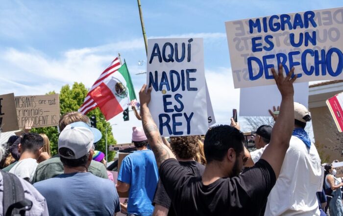 Protesters gather in Santa Cruz on June 14 to oppose President Donald Trump and his policies. A protester holds signs that say in Spanish ‘Here no one is king’ and ‘Migration is a right.’ (Nik Altenberg — Santa Cruz Local file)