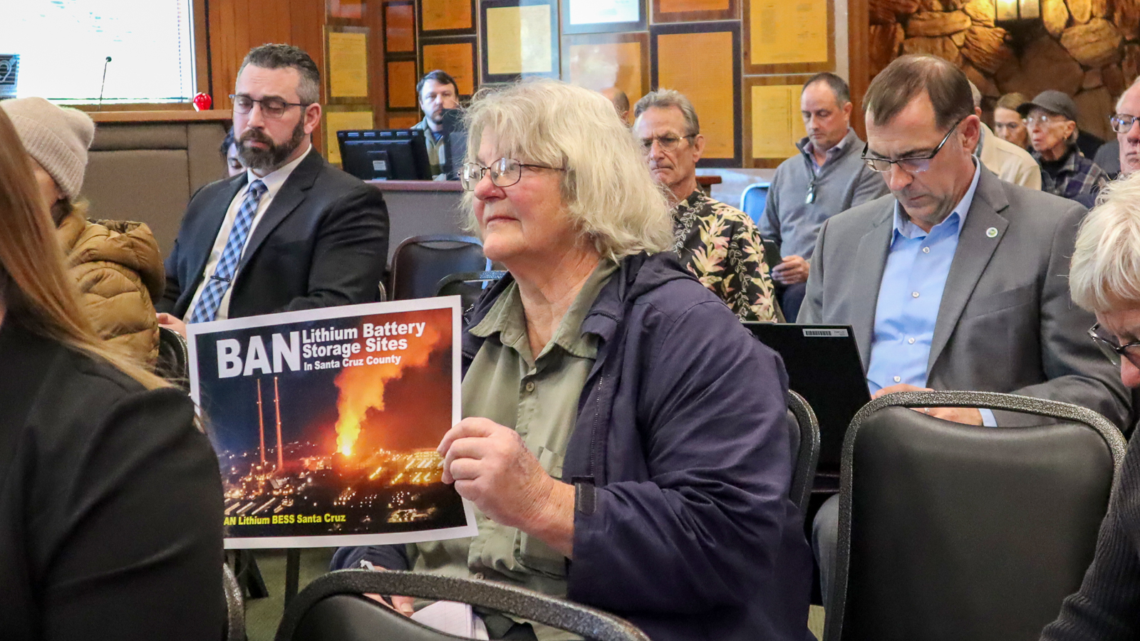 county-supervisors-bess-lithium-battery-jan-13-2026-cannestra-4 County resident Becky Steinbruner holds a sign reading ‘Ban Lithium Battery Storage Sites in Santa Cruz County.’