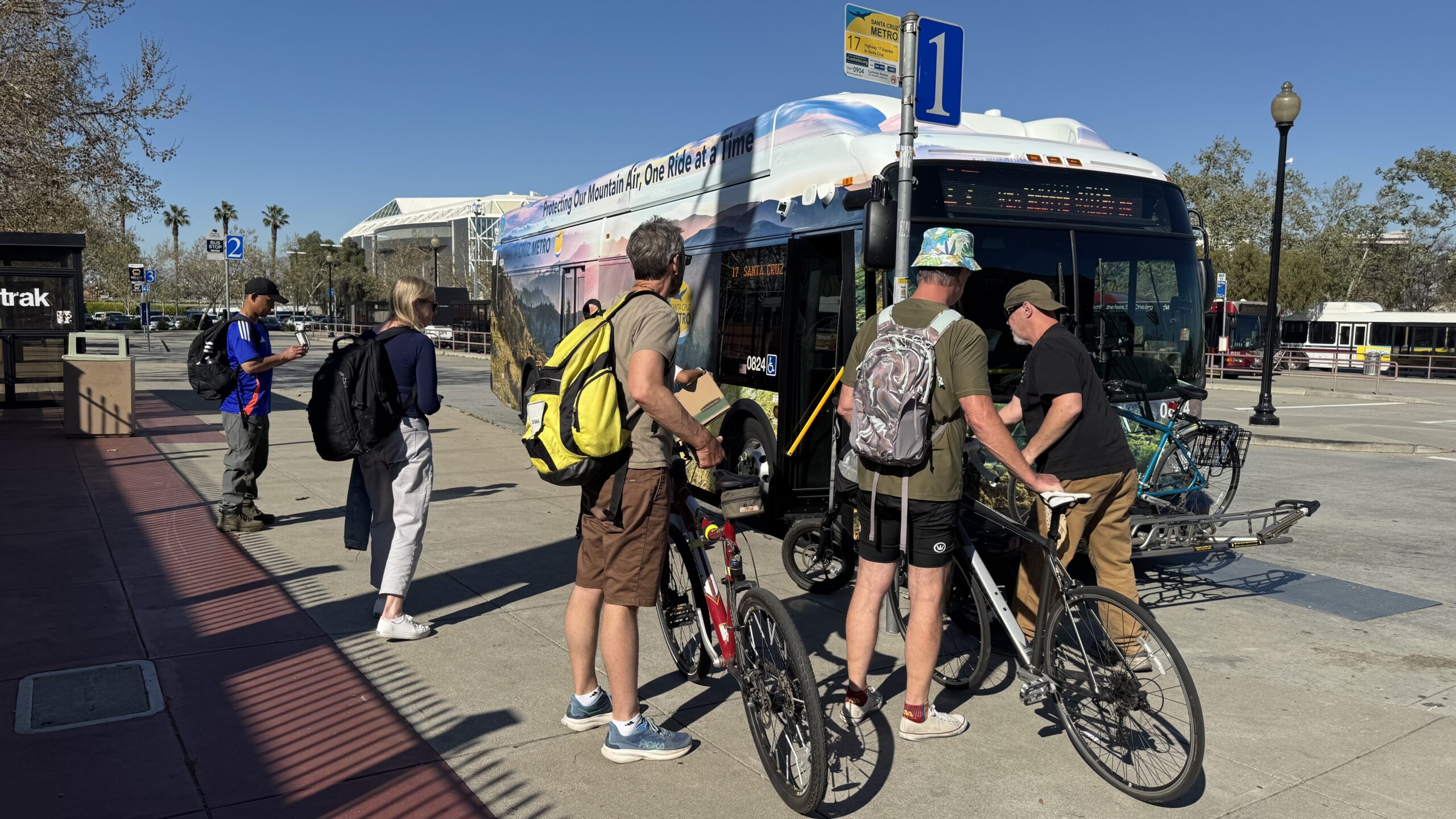 metro-san-jose-march-2025-jk A line of riders queue up outside a Metro bus on a sunny day in San Jose.